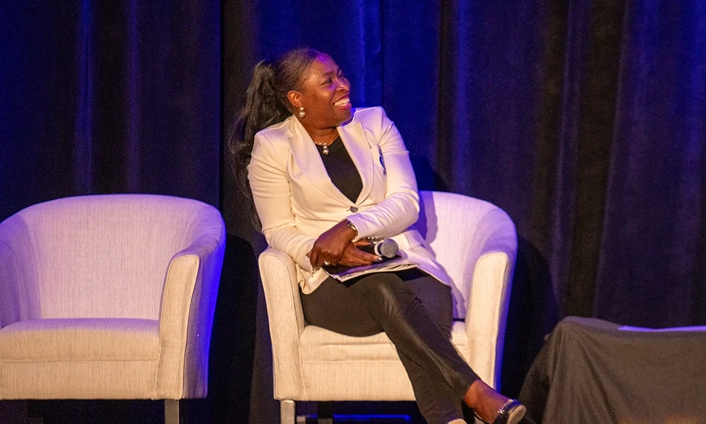 Dr. Olu, sitting on chair on stage during the panel discussion.